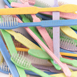 Ein Stapel bunter Zahnbürsten in Pastelltönen wie Grün, Blau, Rosa und Gelb.