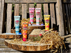 Fünf bunte Tuben Zahnpasta und Zahnbürsten von Dr. Bronner, ausgestellt auf einer rustikalen Holzoberfläche mit Stroh.