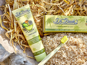 Dr. Bauer’s Citrus Island Zahnpasta, Schachtel und gelbe Zahnbürste auf Holzspänen und Stroh.
