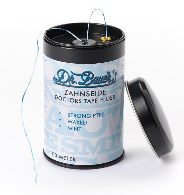 Dr. Bauer's ZS-SPENDER Doctors Floss mint ungewachst 100m abgebildet in einem zylindrischen Behälter mit abgenommenem Deckel und teilweise herausgezogener Zahnseide.