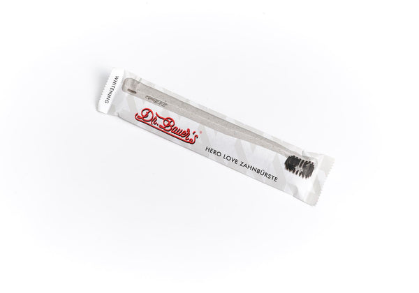 Auf weißem Hintergrund ist eine verpackte Dr. Bauer's Hero Love Whitening Zahnbürste mit superweichen Borsten zu sehen.