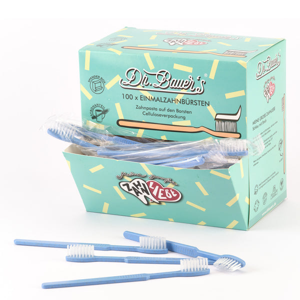 Eine Box Dr. Bauer's Einmalzahnbürsten -STROH- 100er Blau steht mit mehreren blauen Zahnbürsten davor.