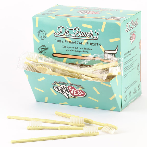 Schachtel mit Dr. Bauer's Einmalzahnbürsten -STROH- 100er Gelb auf weißer Fläche, davor mehrere gelbe Einwegzahnbürsten mit praktischer integrierter Zahnpasta.