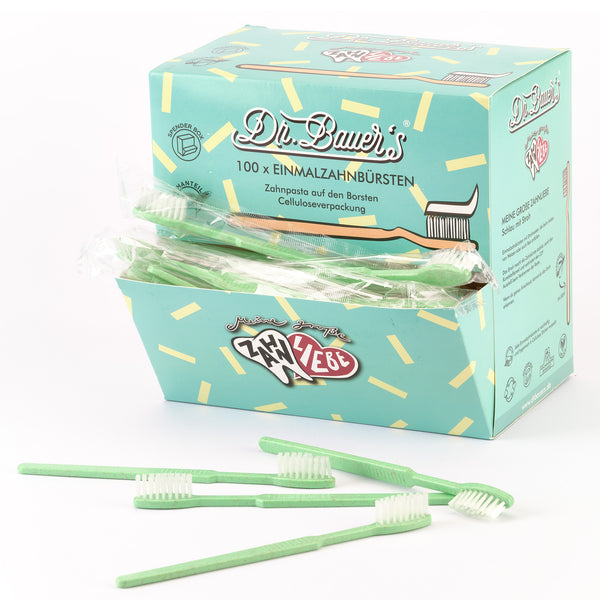 Schachtel von Dr. Bauer's Einmalzahnbürsten -STROH- 100er Grün, mit mehreren losen grünen Einwegzahnbürsten davor.