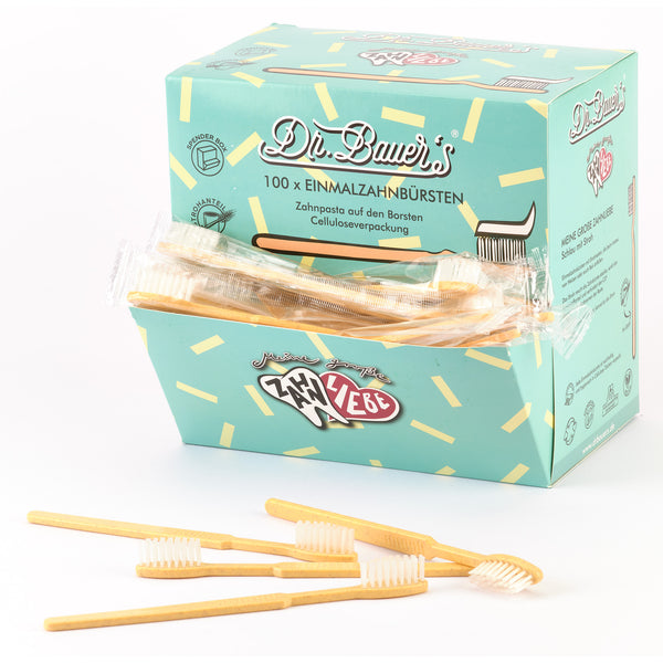 Schachtel Dr. Bauer's Einmalzahnbürsten -STROH- 100er Orange mit mehreren orangefarbenen Einwegzahnbürsten von Dr. Bauer's mit integrierter Zahnpasta, vorne ausgestellt.