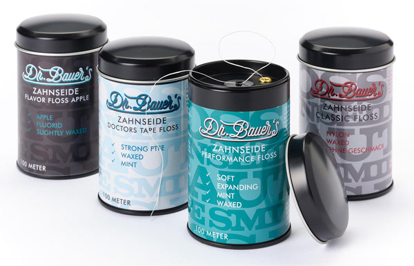 Vier Dosen Dr. Bauer's ZS-SPENDER Flavor Floss Apple 100m, mit sichtbaren Zahnseidenfäden.
