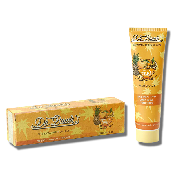 Eine Tube und eine Schachtel Dr. Bauer's Zahnpasta Fruits of Love Fruit Splash 90 ml sind mit Orangen-, Ananas- und Mango-Illustrationen versehen und versprechen sanfte Reinigung und exotische Fruchtaromen.