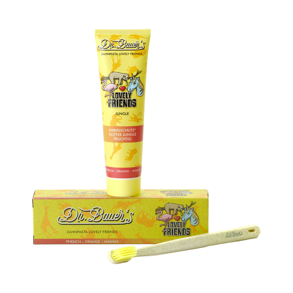 Dr. Bauer‘s Zahnpasta Lovely Friends Jungle 90 ml, die passende Box und eine gelbe Zahnbürste auf weißem Grund – ideal zum Zähneputzen und zur Erhaltung gesunder Kinderzähne.