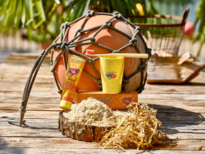 Hautpflegeprodukte und eine gelbe Tasse auf Holz mit Stroh, einer Netzboje und einer Palme im Hintergrund.