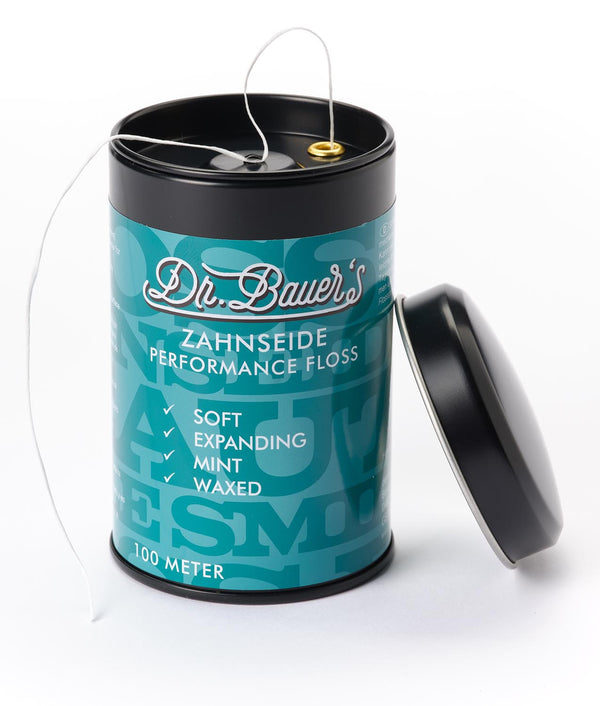 Ein tealfarbener Dr. Bauer's ZS-SPENDER Performance Floss 100m Behälter mit abgenommenem Deckel und teilweise herausgezogener Zahnseide.