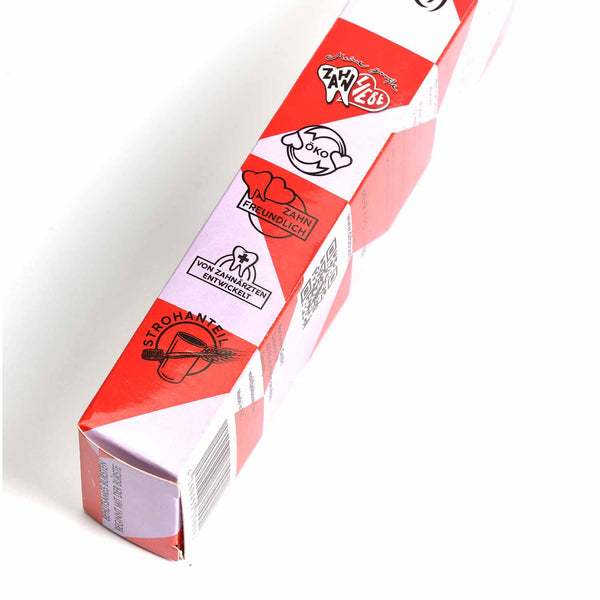 Eine rot-weiße Softbox der Dr. Bauer’s Soft Kiss Zahnbürste zeigt zahnmedizinische und umweltfreundliche Symbole sowie deutschen Text und hebt diese nachhaltige Zahnbürste hervor, die aus umweltfreundlichen Materialien hergestellt wurde.