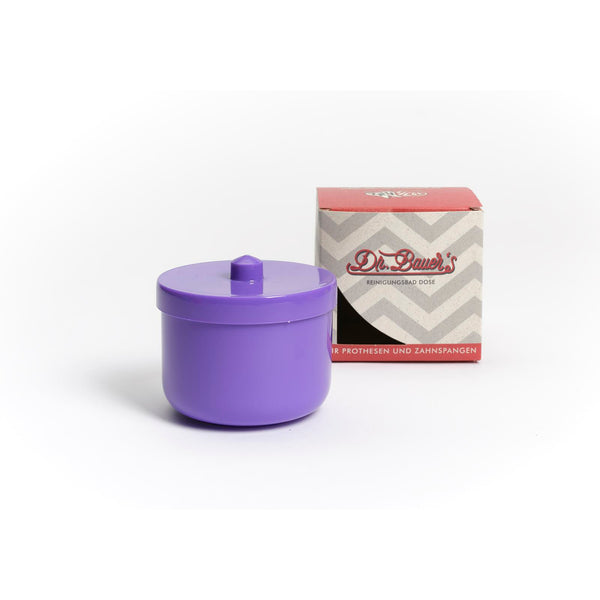 Eine Dr. Bauer's Reinigungsbad-Dose in flieder/lila, ideal für Zahnspangen oder Prothesen-Reinigungsbad, sitzt neben einer rot-grauen Dr. Bauer's Box auf weißem Hintergrund.