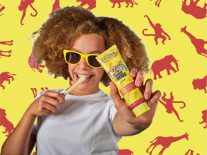 Ein Kind das die Zahnpasta Tupen Lovely Friends Jungle in die Kamera hält.