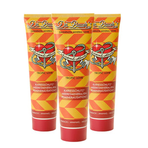 Die drei Tuben von Dr. Bauer's Zahnpasta Mineral Love Tropic Love (je 90 ml) in der leuchtend orange-gelb gestreiften Verpackung sind speziell für empfindliche Zähne mit natürlichen Meeresmineralien formuliert.