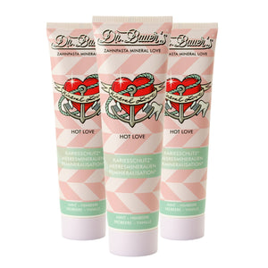 Dreierpack Dr. Bauer's Zahnpasta Mineral Love Hot Love (je 90ml) mit Herz- und Ankermotiv auf rosa-weißer Verpackung - ideal für besondere Zahnpflege-Momente.