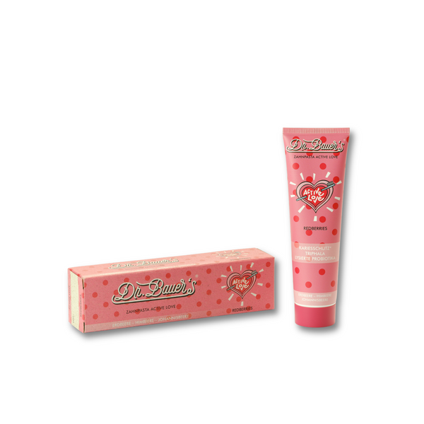 Dr. Bauer's Zahnpasta Active Love Redberries 90ml Cremetube und Dose, mit Herzmotiv und Probiotika für optimale Mundgesundheit, auf weißem Hintergrund.