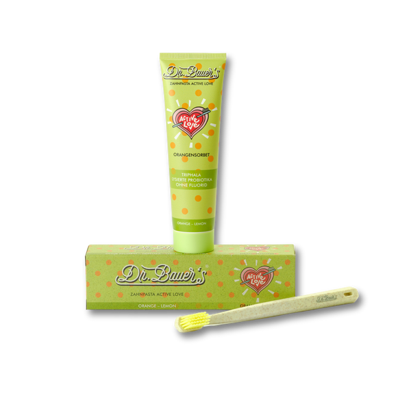 Dr. Bauer's Zahnpasta Active Love Orangen Sorbet 90ml in einer grünen Tube mit passender Schachtel und gelber Zahnbürste für die Zahnpflege, abgebildet auf schwarzem Hintergrund.