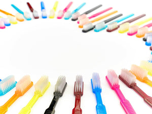 Dr. Bauer's Einmalzahnbürsten mit Zahnpasta 100er Packung PINK, farbenfrohe Einweg-Zahnbürsten, halbkreisförmig auf weißem Hintergrund angeordnet, lassen in der Mitte Raum frei.