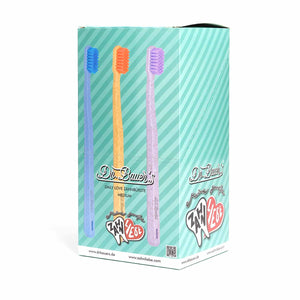 Schachtel mit drei Dr. Bauer's Daily Love Zahnbürsten medium mit biobasierten Borsten und Dr. Bauer's Branding, dargestellt auf einem teal gestreiften Hintergrund.