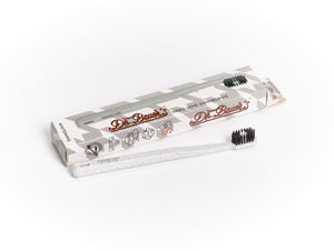 Eine Dr. Bauer's Hero Love Whitening Zahnbürste mit schwarzen, superweichen Borsten steht neben der Dr. Bauer's Markenbox auf weißem Hintergrund.