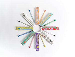 Dr. Bauer‘s Hero Love Whitening Zahnbürste von Dr. Bauer‘s, mit Supersoftborsten und bunten passenden Boxen, angeordnet in einem kreisförmigen Muster auf weißem Hintergrund.