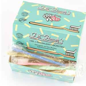 Schachtel Dr. Bauer's Einmalzahnbürsten -STROH- 100er MIX (blau, grün, gelb, rot) mit verpackten Einwegzahnbürsten mit sichtbar integrierter Zahnpasta auf der Vorderseite der Schachtel.