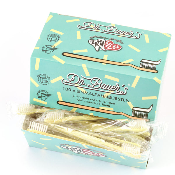 Schachtel mit 100 Dr. Bauer's Einmalzahnbürsten -STROH- in gelb, jeweils mit integrierter Zahnpasta und einzeln verpackt in biologisch abbaubarer Verpackung; mit Zahngrafik auf türkisfarbener Schachtel.