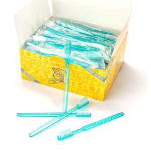 Eine gelbe Schachtel Dr. Bauer's Einmalzahnbürsten100er MIX (blau-grün-rot-gelb) von Dr. Bauer's, darin einzeln verpackte, transparente Zahnbürsten in Blau, Grün, Rot und Gelb mit einigen vorne liegenden Bürsten.