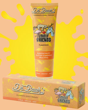Tube und Schachtel von Dr. Bauers Flamingo Zahnpasta mit bunten Tierillustrationen auf gelbem Hintergrund.