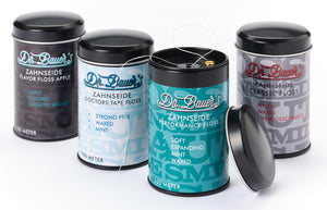 Vier Dosen Dr. Bauer's ZS-SPENDER Flavor Floss Apple 100m, mit sichtbaren Zahnseidenfäden.