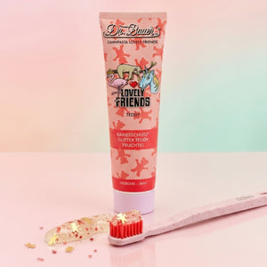 Dr. Bauer's Zahnpasta Lovely Friends Teddy 90ml zeigt eine verspielte Tiergrafik auf einer rosafarbenen Tube mit moderner serifenloser Schrift, gepaart mit einer rosafarbenen Zahnbürste mit roter Zahnpasta - so macht das Zähneputzen Spaß für Kinder.