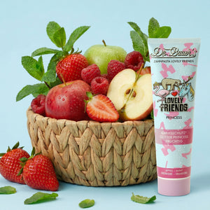 Ein geflochtener Korb mit Äpfeln und Erdbeeren steht neben Dr. Bauer's Zahnpasta Lovely Friends Prinzessin 90ml, gestylt in einem klaren, serifenlosen Look, inspiriert von Schriftarten wie Helvetica Neue.