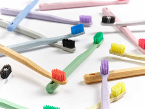 Mehrere Dr. Bauer's Soft Kiss Zahnbürsten von Dr. Bauer's mit biobasiertem Borsten und bunten Borsten sind auf einer weißen Fläche verteilt, um ihre umweltfreundlichen Materialien hervorzuheben.