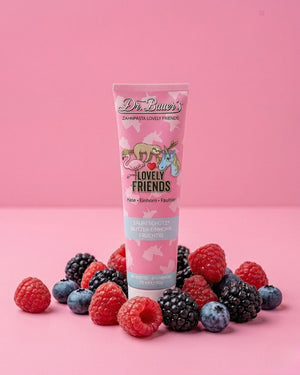 Eine Tube Dr. Bauer's Lovely Friends Zahnpasta, umgeben von Himbeeren, Brombeeren und Heidelbeeren.